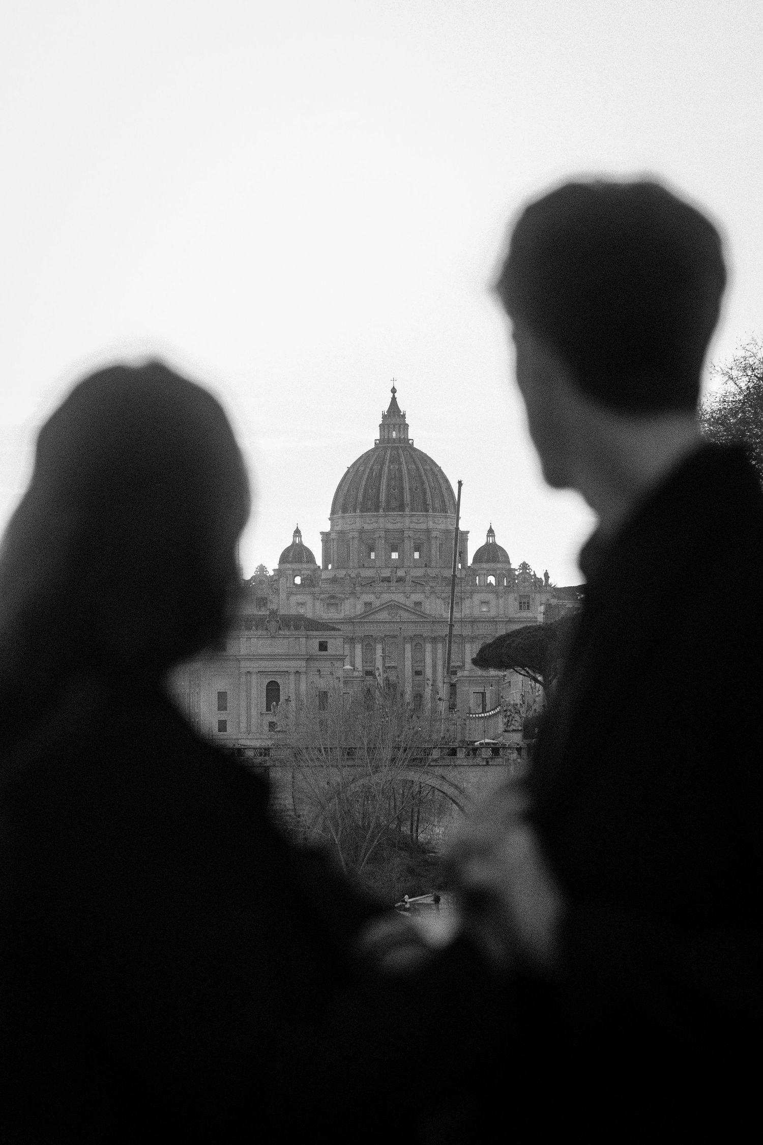 A black and white silhouette of two people viewing St. Peter's Basilica in Vatican City.