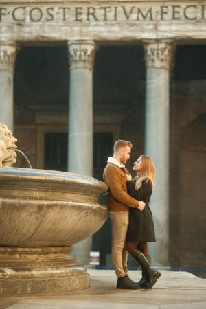 A romantic moment by an ancient fountain with classical columns in the background.