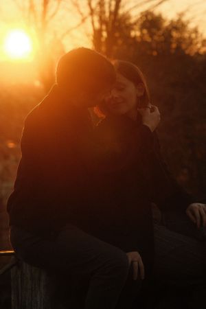 Silhouetted figures share an intimate moment during a golden sunset.
