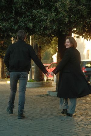Two people holding hands while walking on a cobblestone path during golden hour.