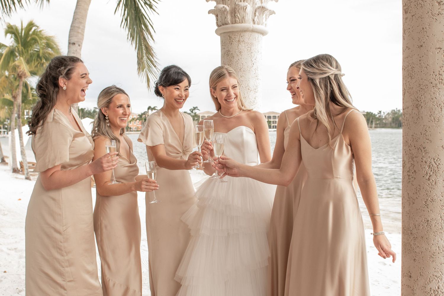bride and bridesmaids on wedding day cheers with champagne at miromat lakes beach club in Florida