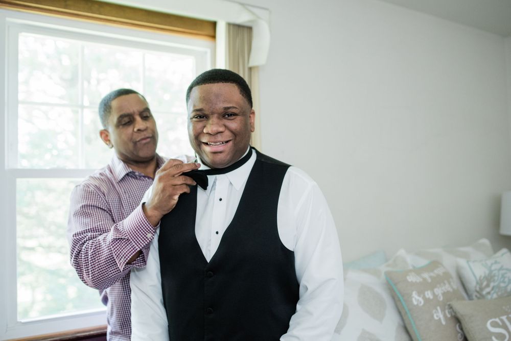 father of the groom helping groom with bow tie