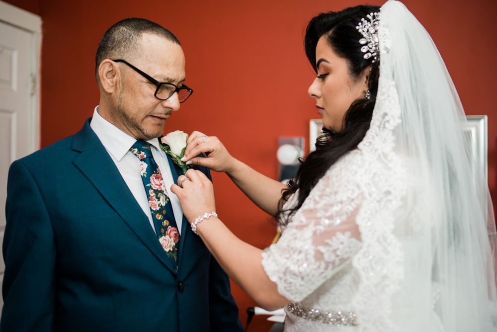 bride putting boutonnière on dad