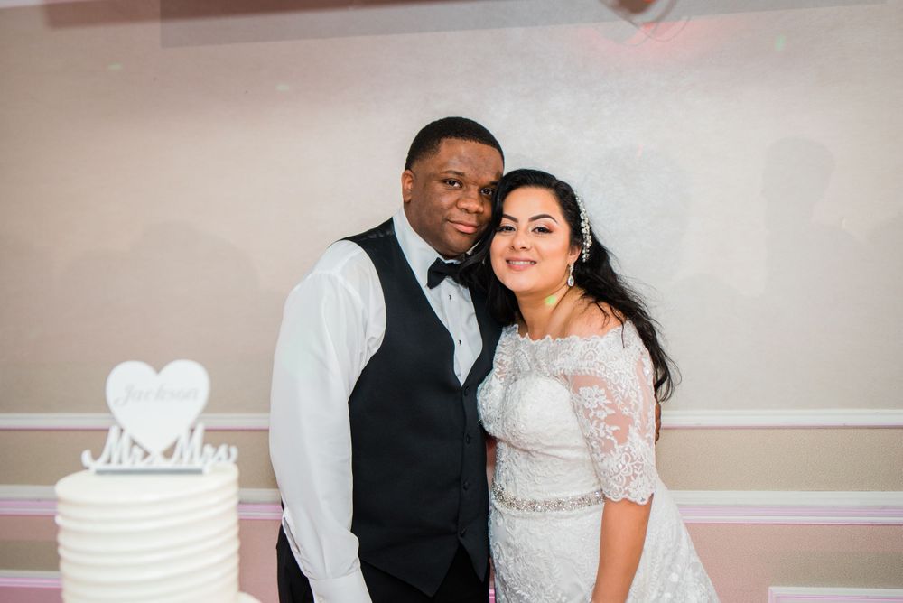bride and groom posing next to wedding cake