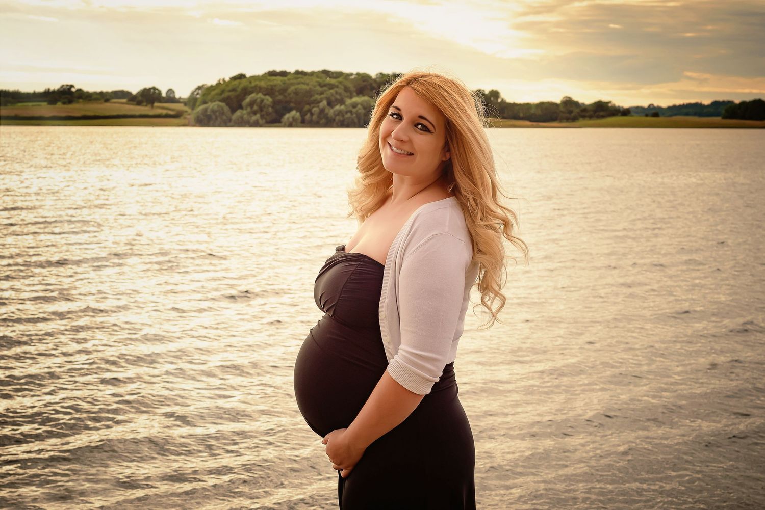 Maternity portrait at sunset by the water wearing black and white outfit.