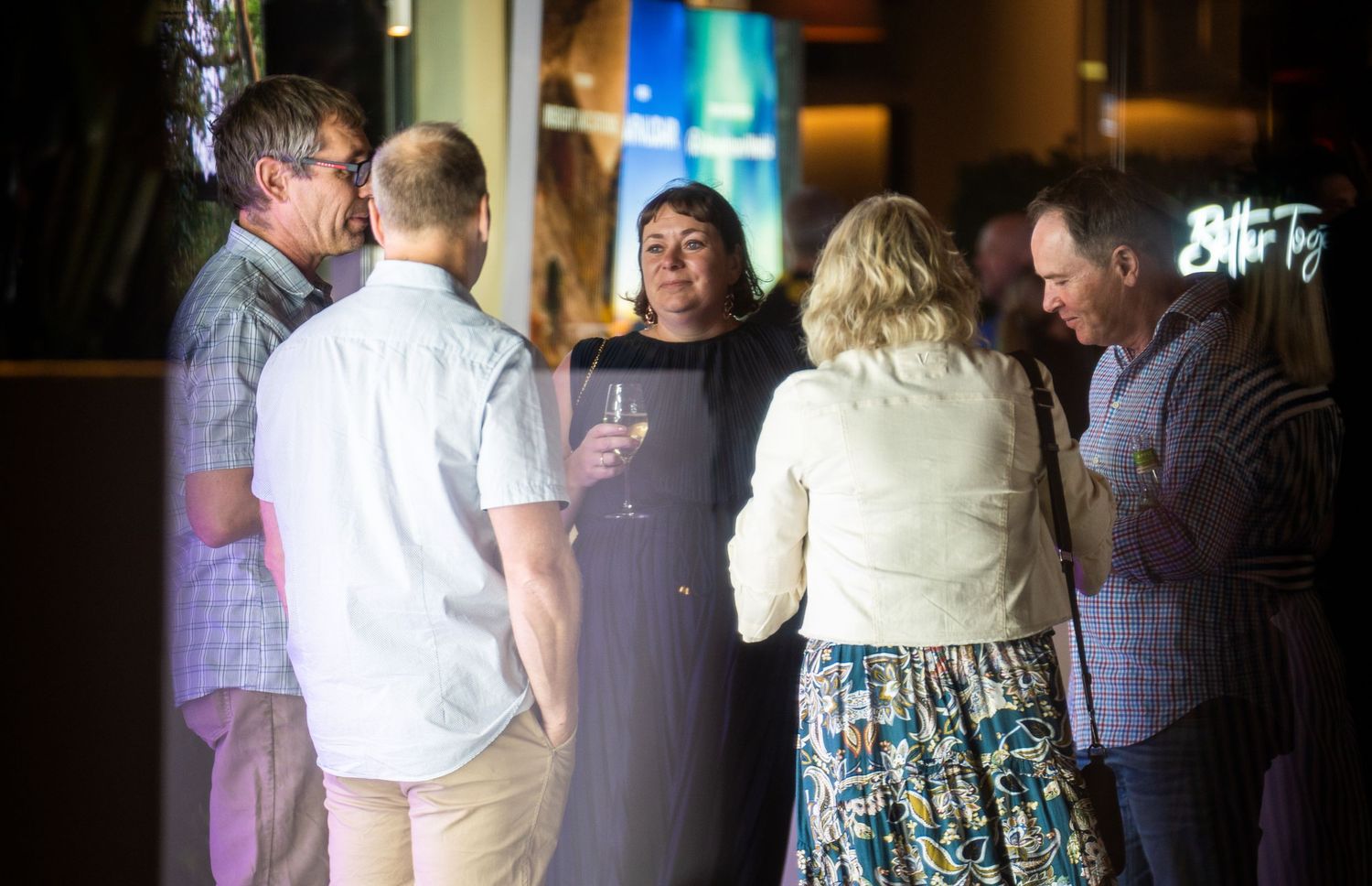 People mingling at an indoor social event with ambient lighting.