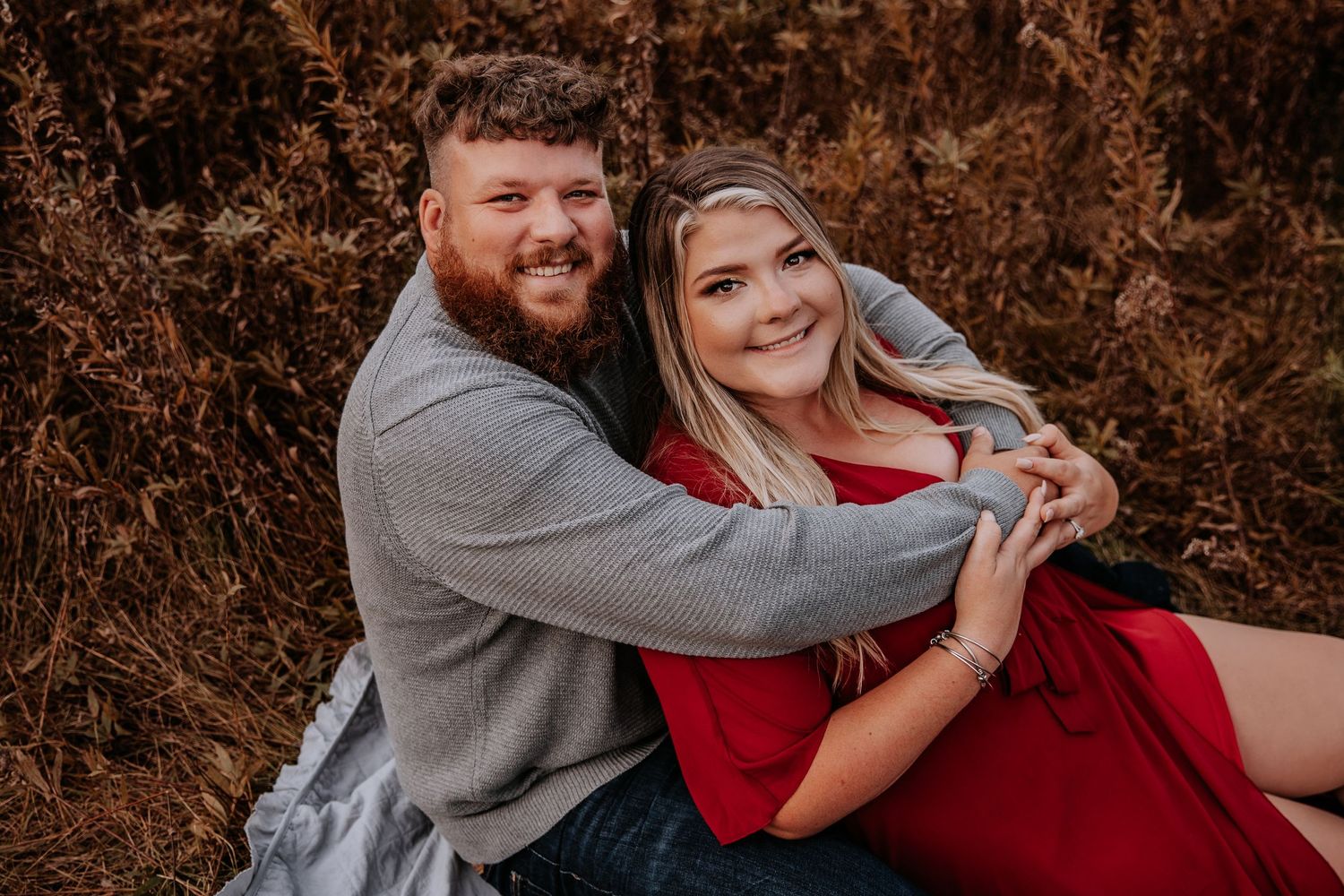 A couple poses together against a backdrop of rustic fall foliage.