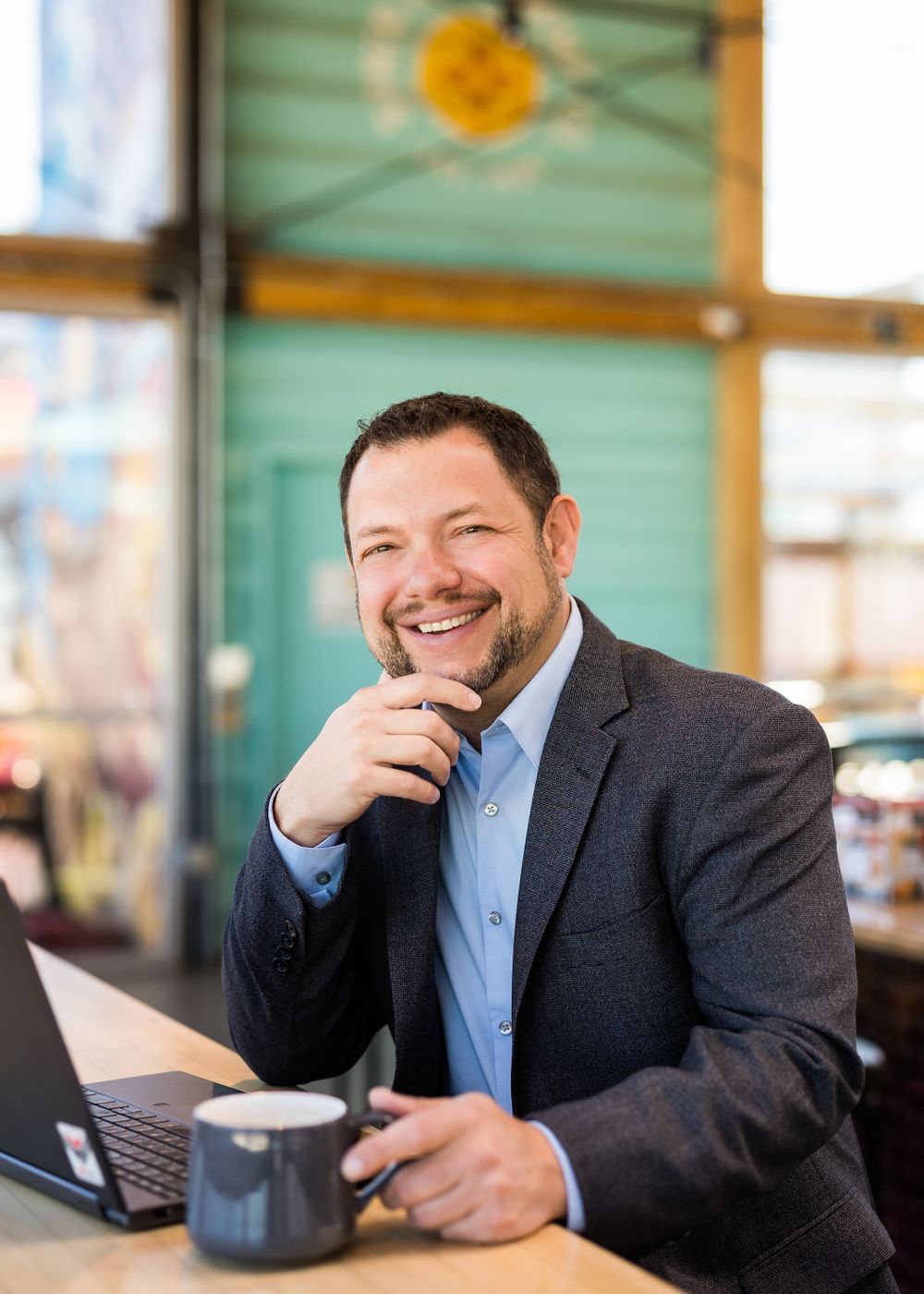 Business professional working on laptop at cafe with cheerful expression.