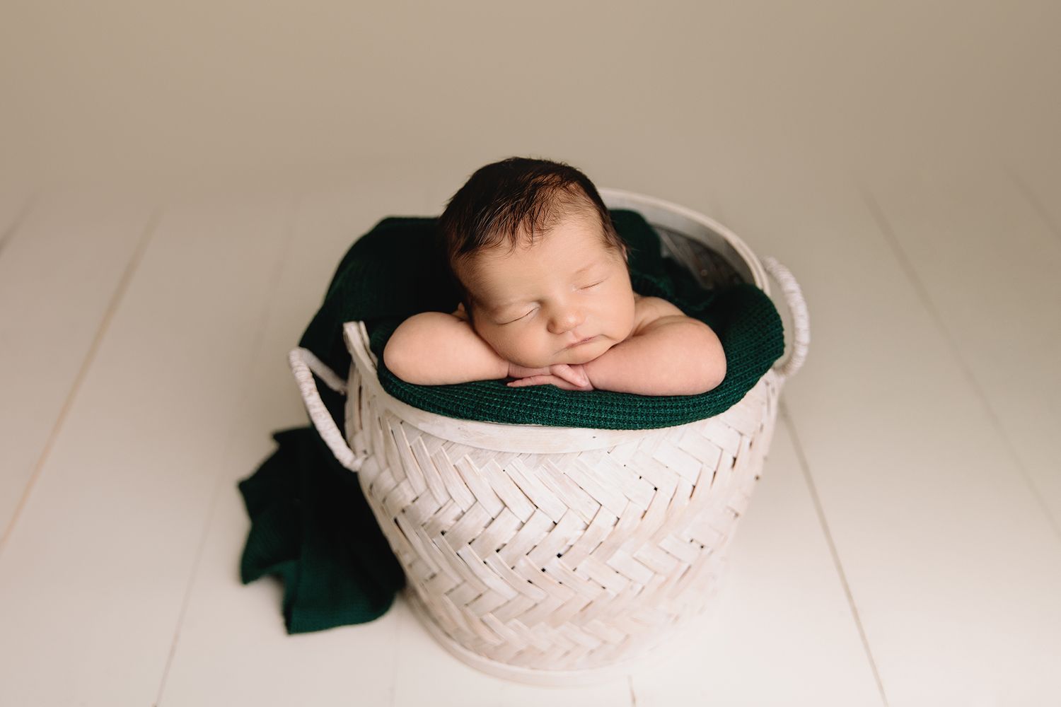 newborn baby sleeping in white basket posed for professional newborn photography session in KC, Missouri