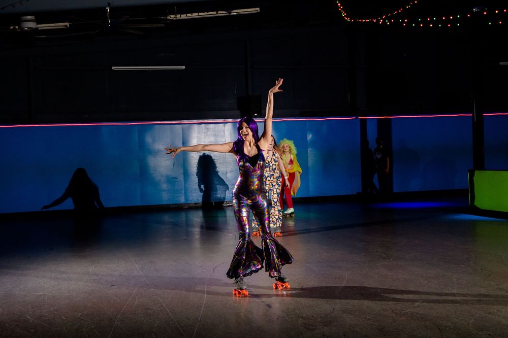 Two roller skaters perform synchronized dance moves under dramatic lighting.