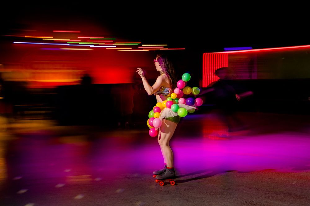 Dynamic shot of roller skater in neon outfit performing against vibrant red and purple lighting.