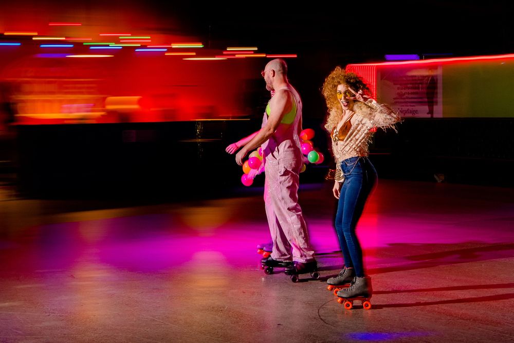Two roller skaters dance together on illuminated rink with motion blur effects.