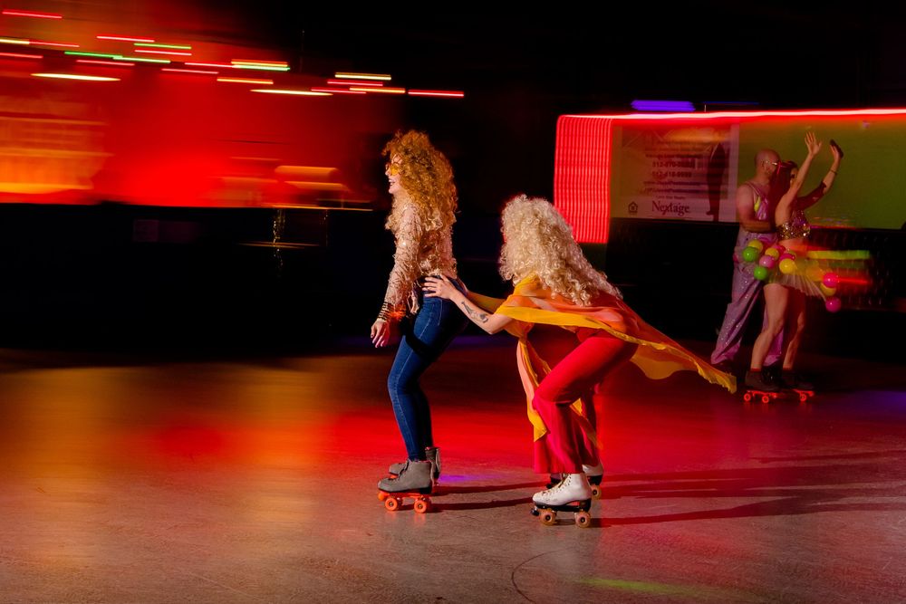 Roller skaters perform synchronized moves against dramatic red lighting at roller rink.