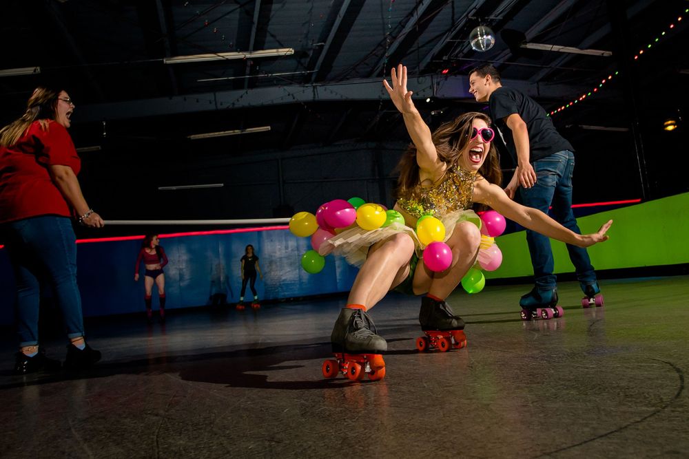 Roller skater performs dramatic fall during choreographed routine at indoor rink.