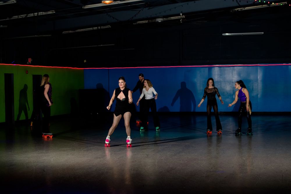 Roller skaters practice choreography on a dark rink with colorful wall accents.