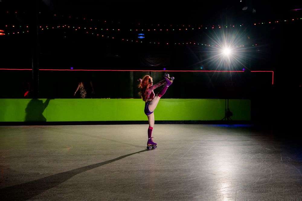 Silhouetted figure on roller skates performs dramatic pose under spotlight.