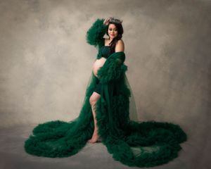 Artistic maternity photo with flowing emerald green tulle robe showing leg through slit.