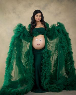 Creative maternity portrait in emerald green gown with painted face design on belly.