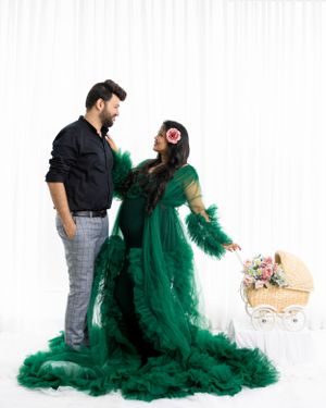 Couple posing in studio with ornate emerald green tulle gown and decorative basket.