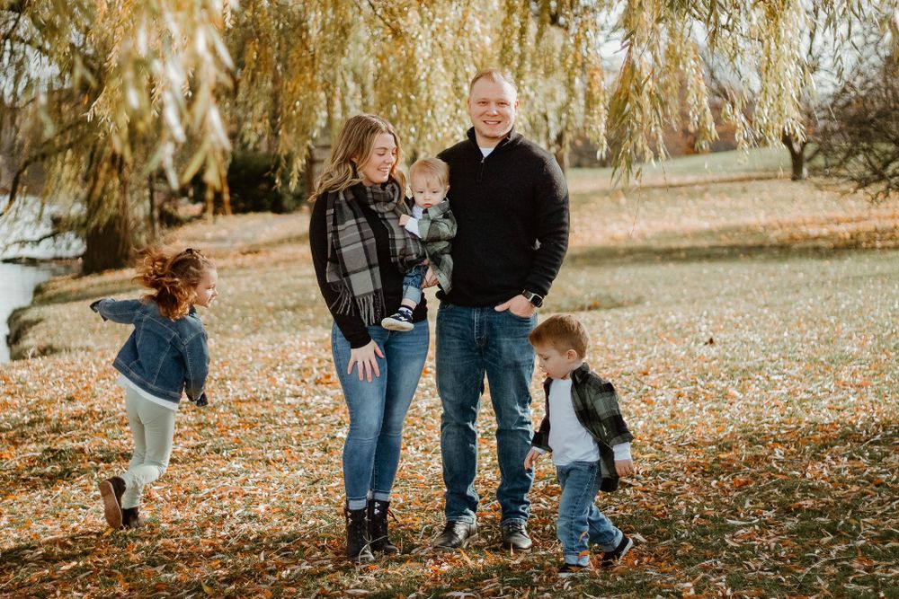 A family enjoys quality time together under a weeping willow tree in autumn.
