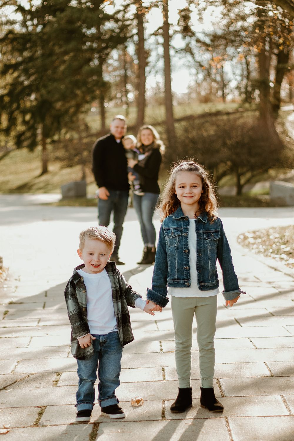 People walking together on stone path surrounded by trees and fallen leaves.