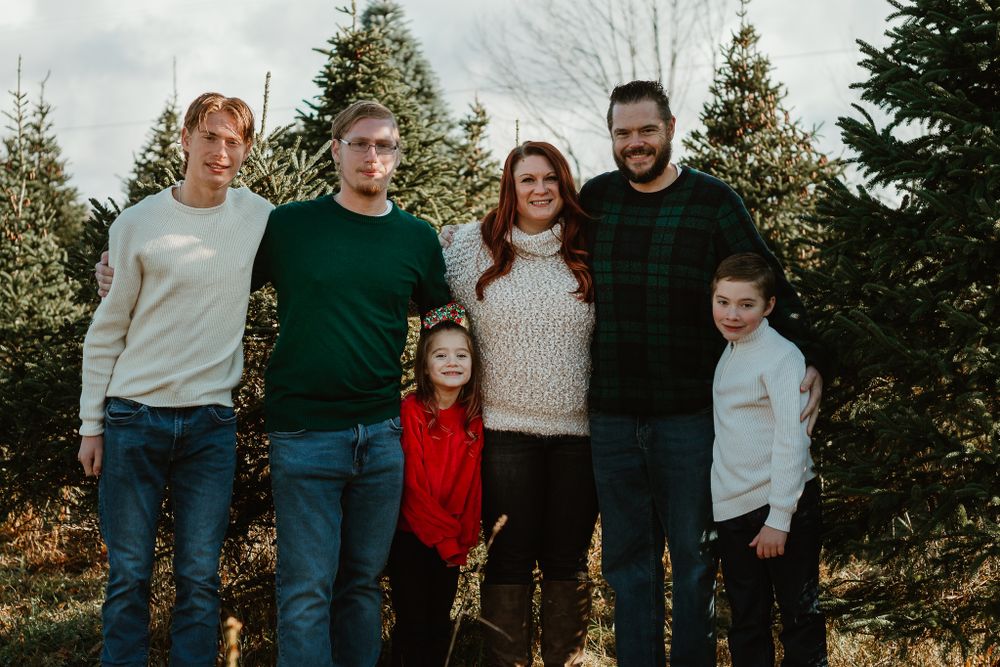 Group portrait taken outdoors with evergreen trees in the background.