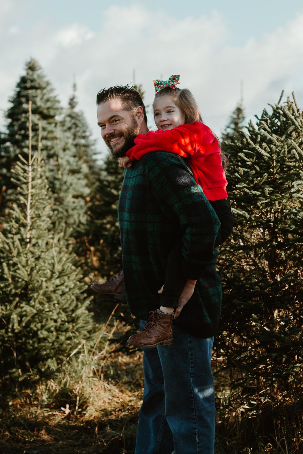 Candid family moments captured among evergreen trees on a bright winter day.