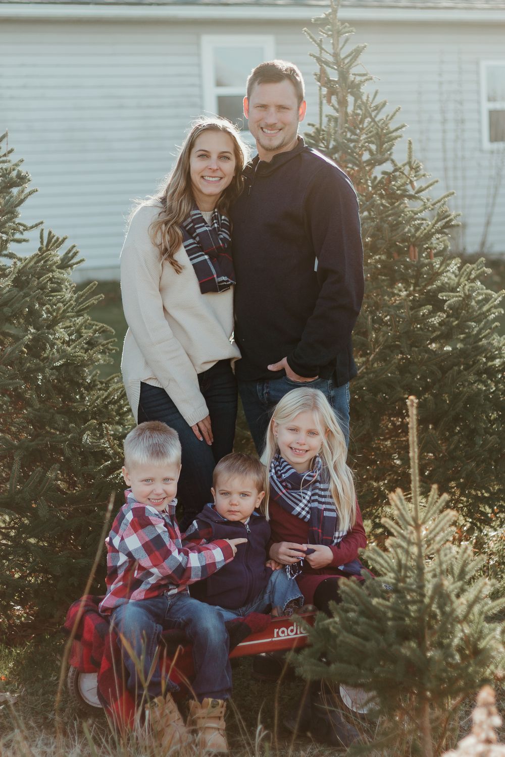 Family gathers around a Christmas tree during a festive outdoor photoshoot.