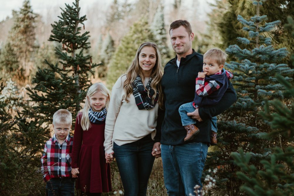 Family poses together among evergreen trees during an outdoor photo session.