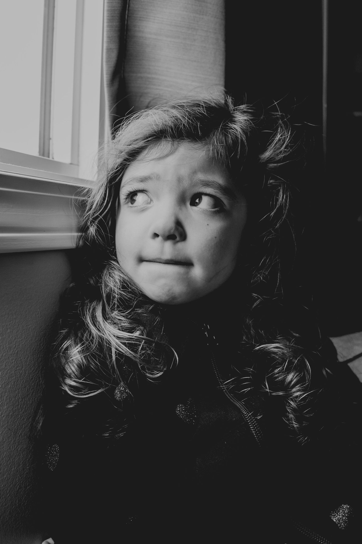 A dramatic black and white portrait near a window creating moody lighting and shadows.