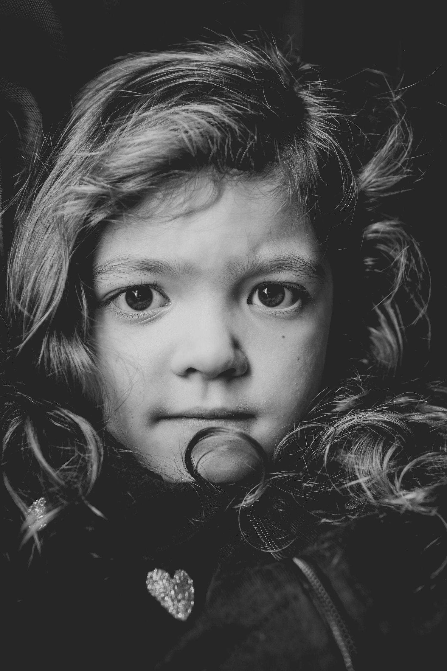 An artistic black and white close-up portrait with curly hair framing the face.