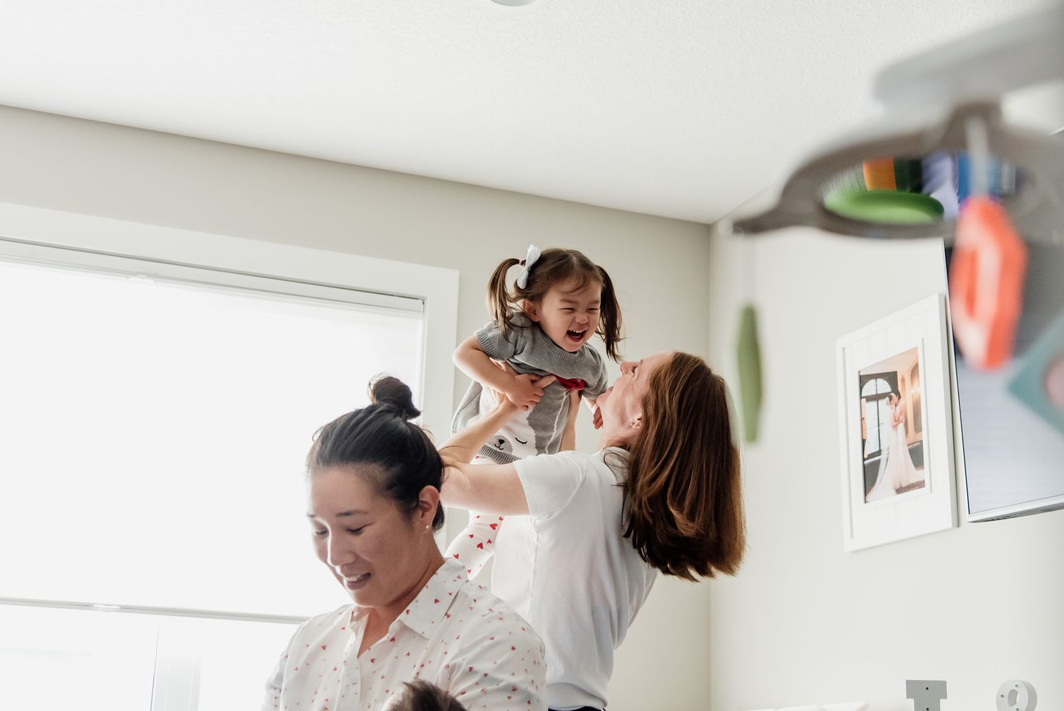 A tender parenting moment captured in a bright room with toys and decorations.
