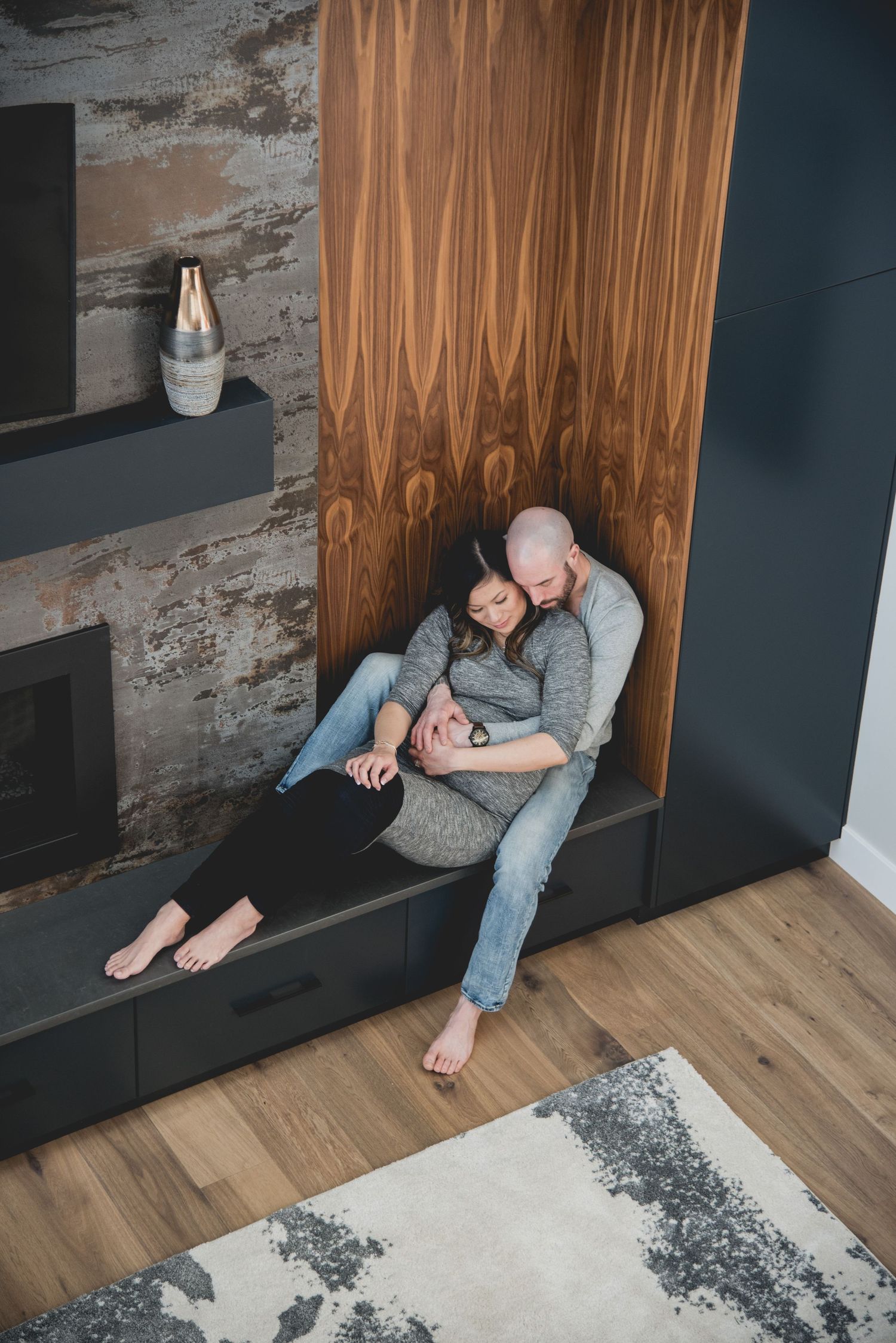 A couple relaxing together on a modern wooden bench with geometric wall panels.