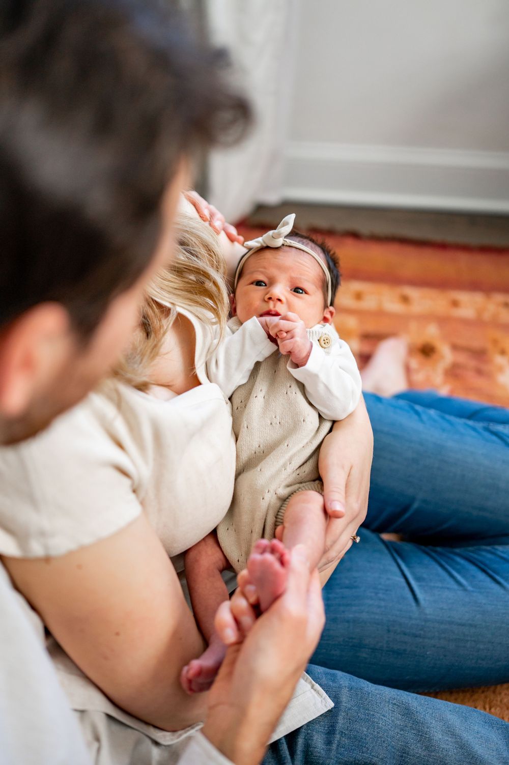 Sweet newborn baby in white onesie being held while making an expressive face.