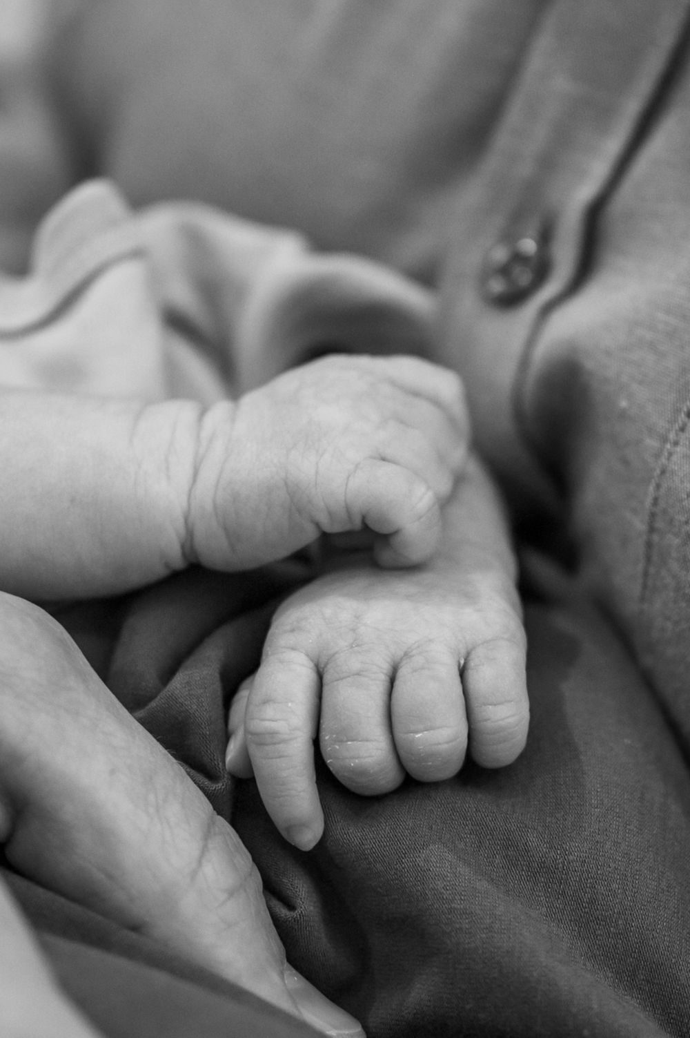 Close up black and white photo of tiny baby hands resting.