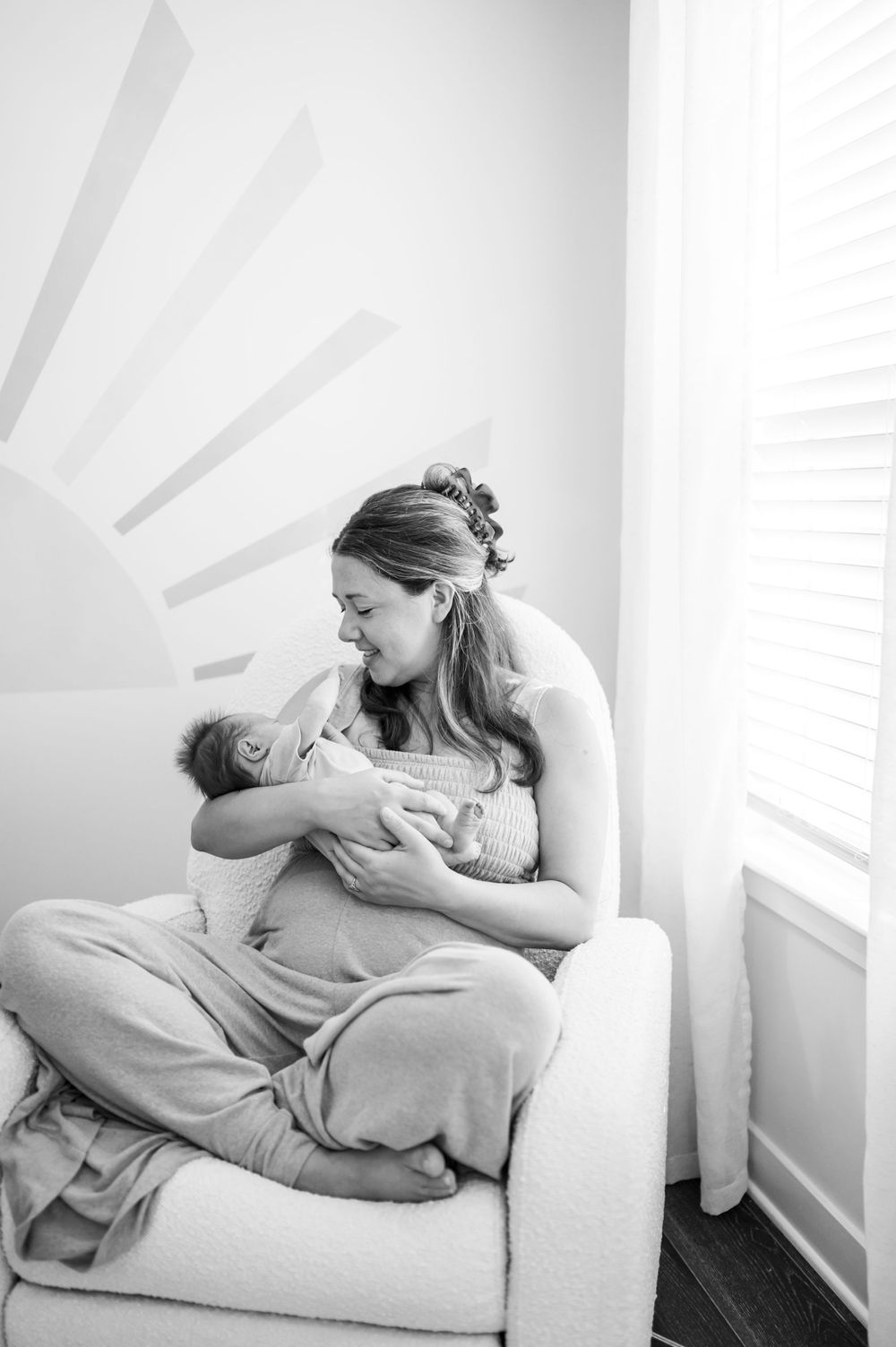 Black and white photo of intimate bonding moment in nursery chair.