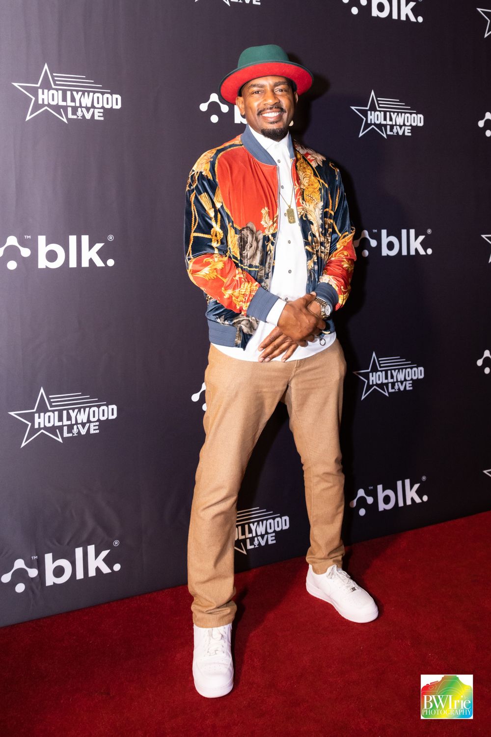 Energetic guest poses in colorful jacket and khakis at Hollywood Live red carpet event.