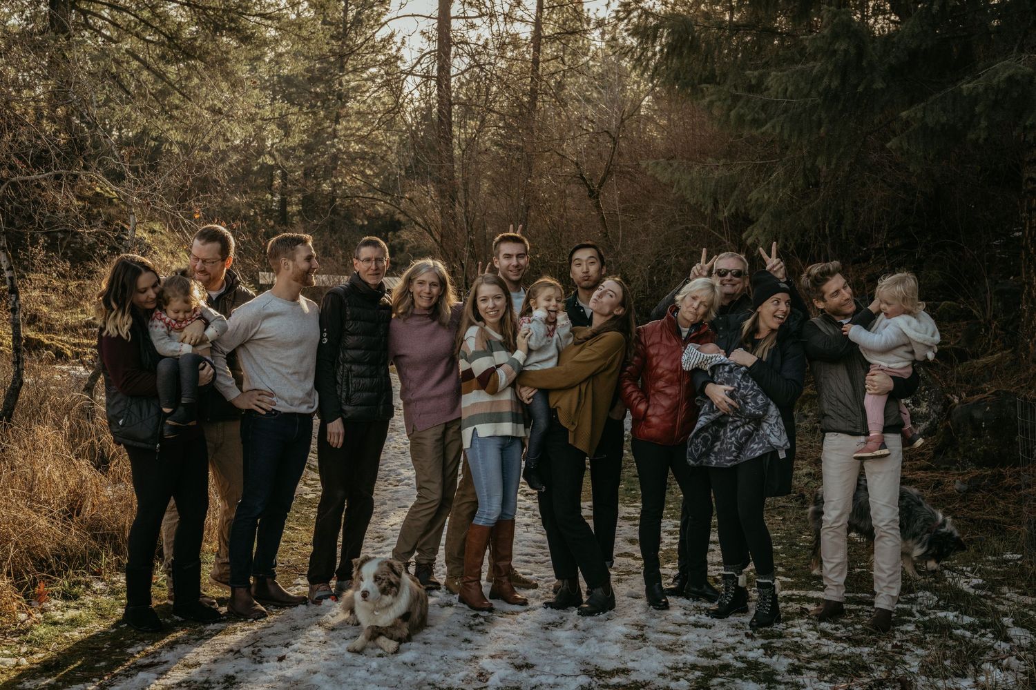 Large group gathered outdoors for a family photo in woodsy setting at sunset.