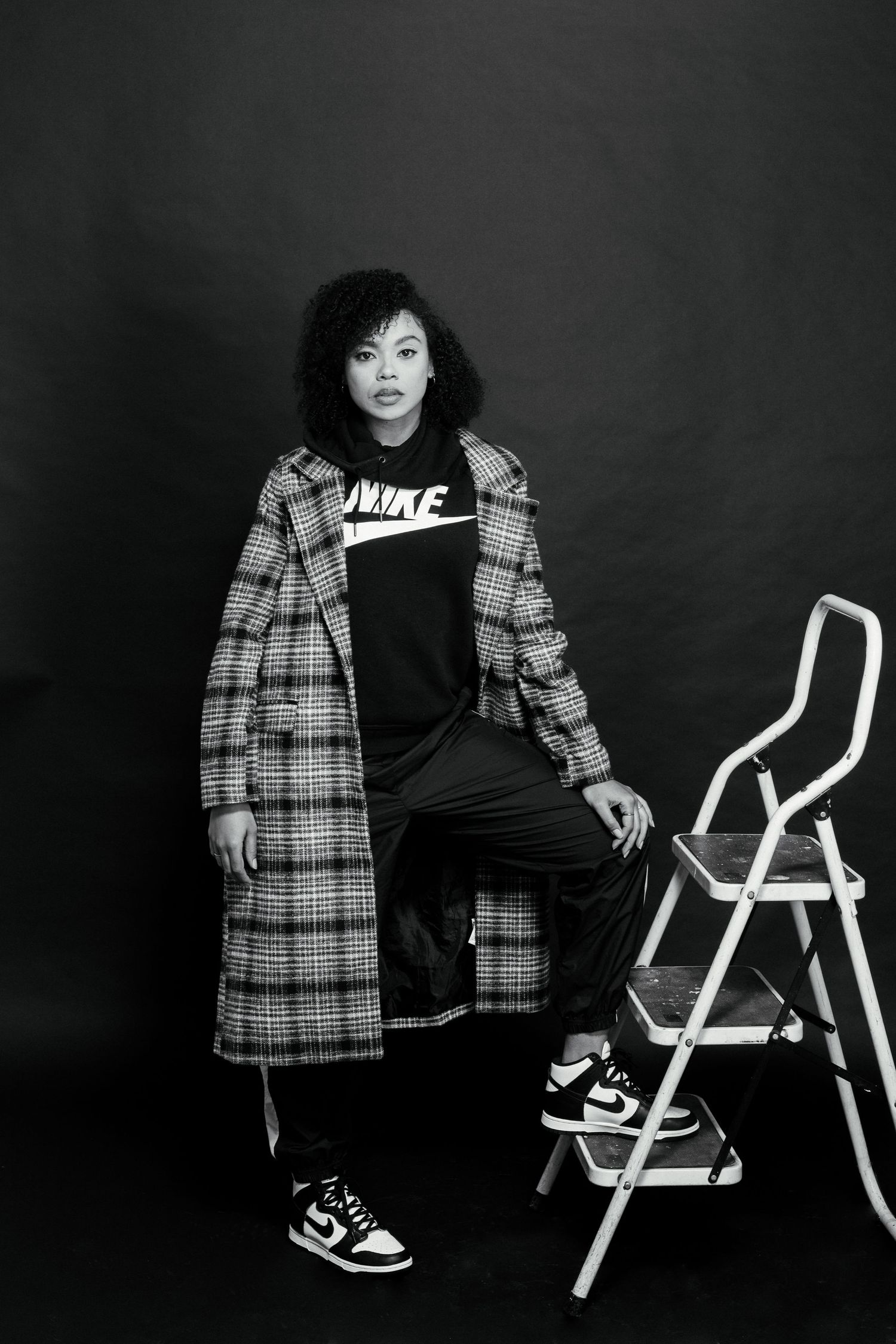 Black and white portrait series showing a person in plaid coat posing with a white chair.
