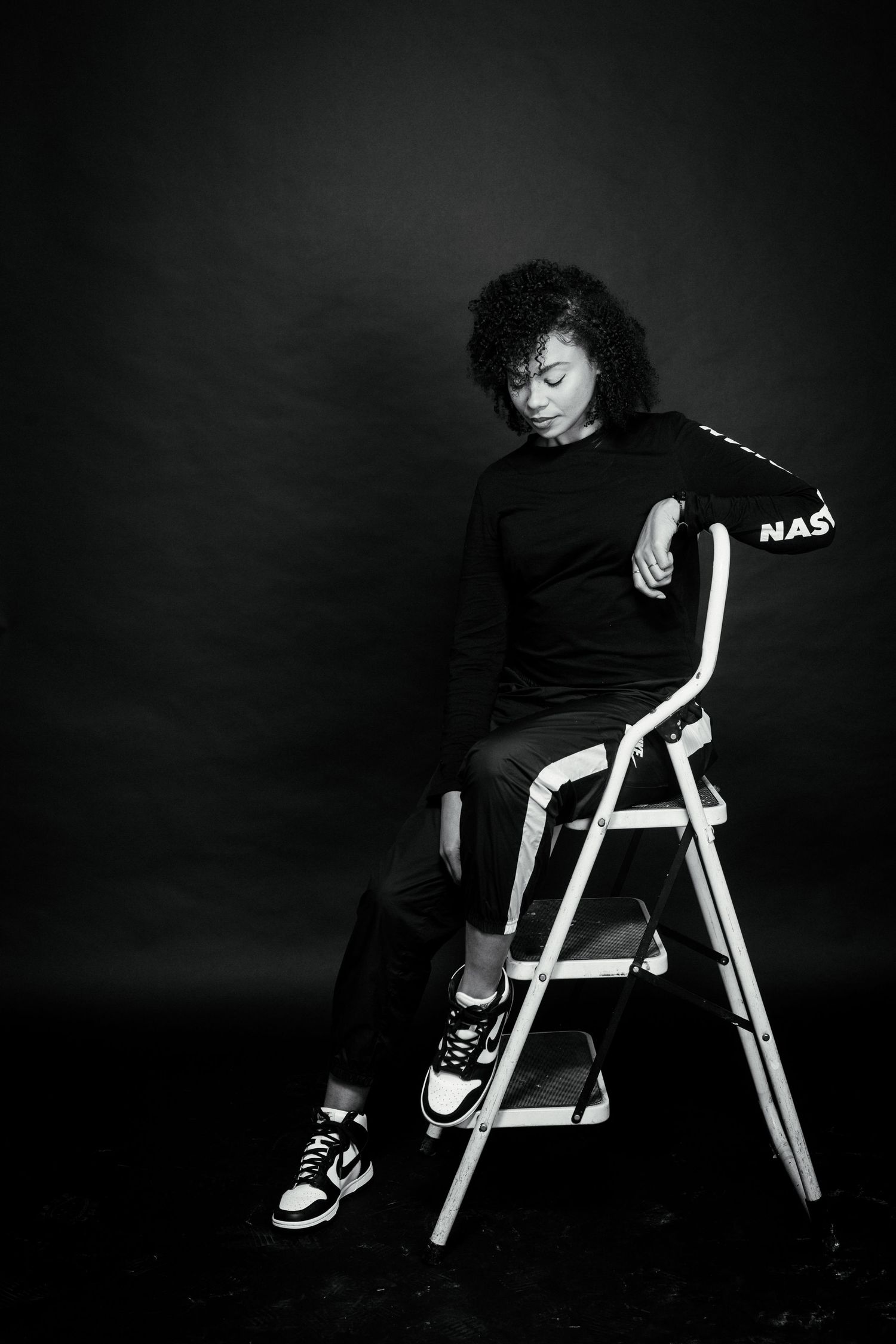 Artistic black and white photo series showing a person in dark clothing sitting on a white folding chair.