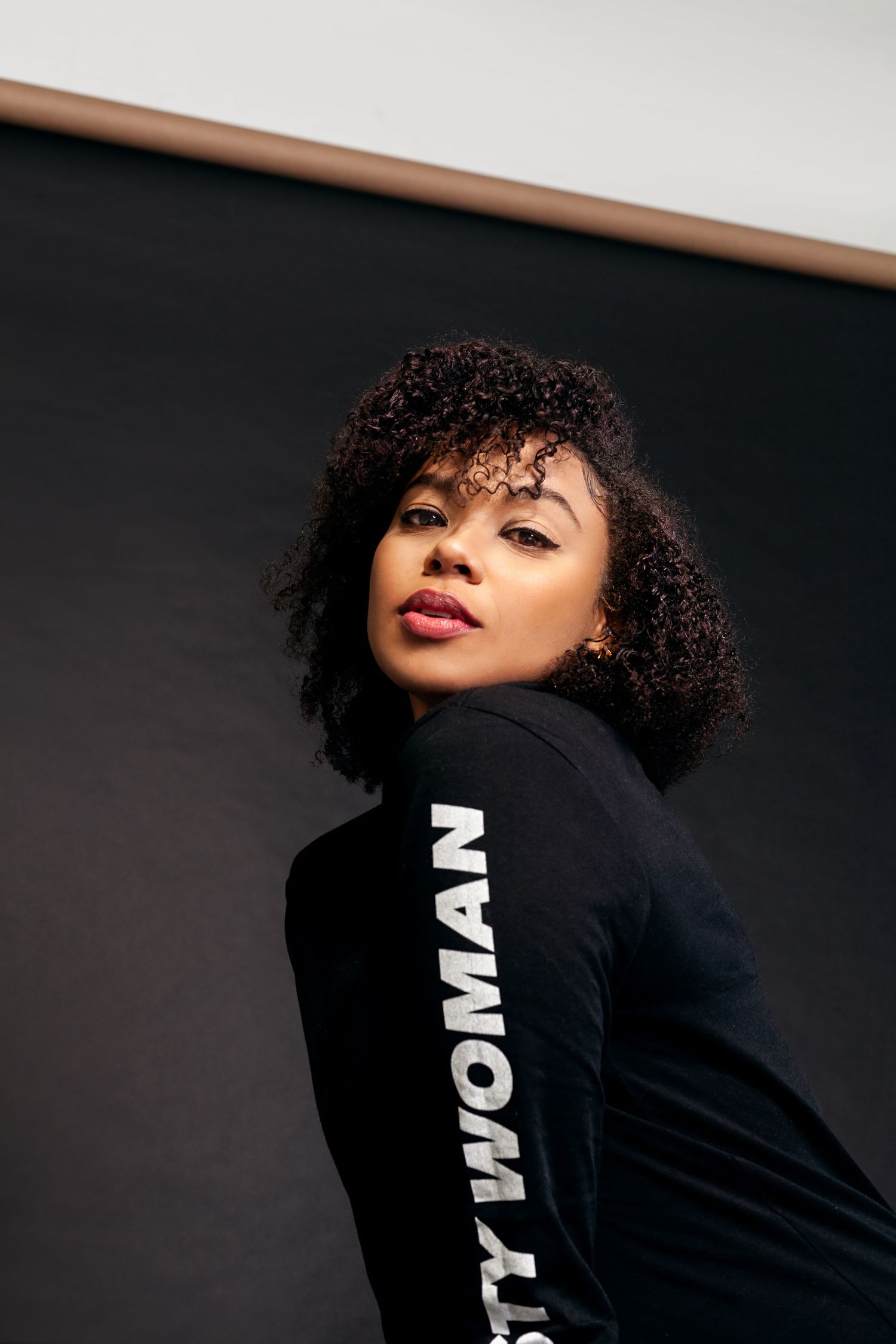 Urban fashion portrait with black athletic wear and natural curly hair styling.
