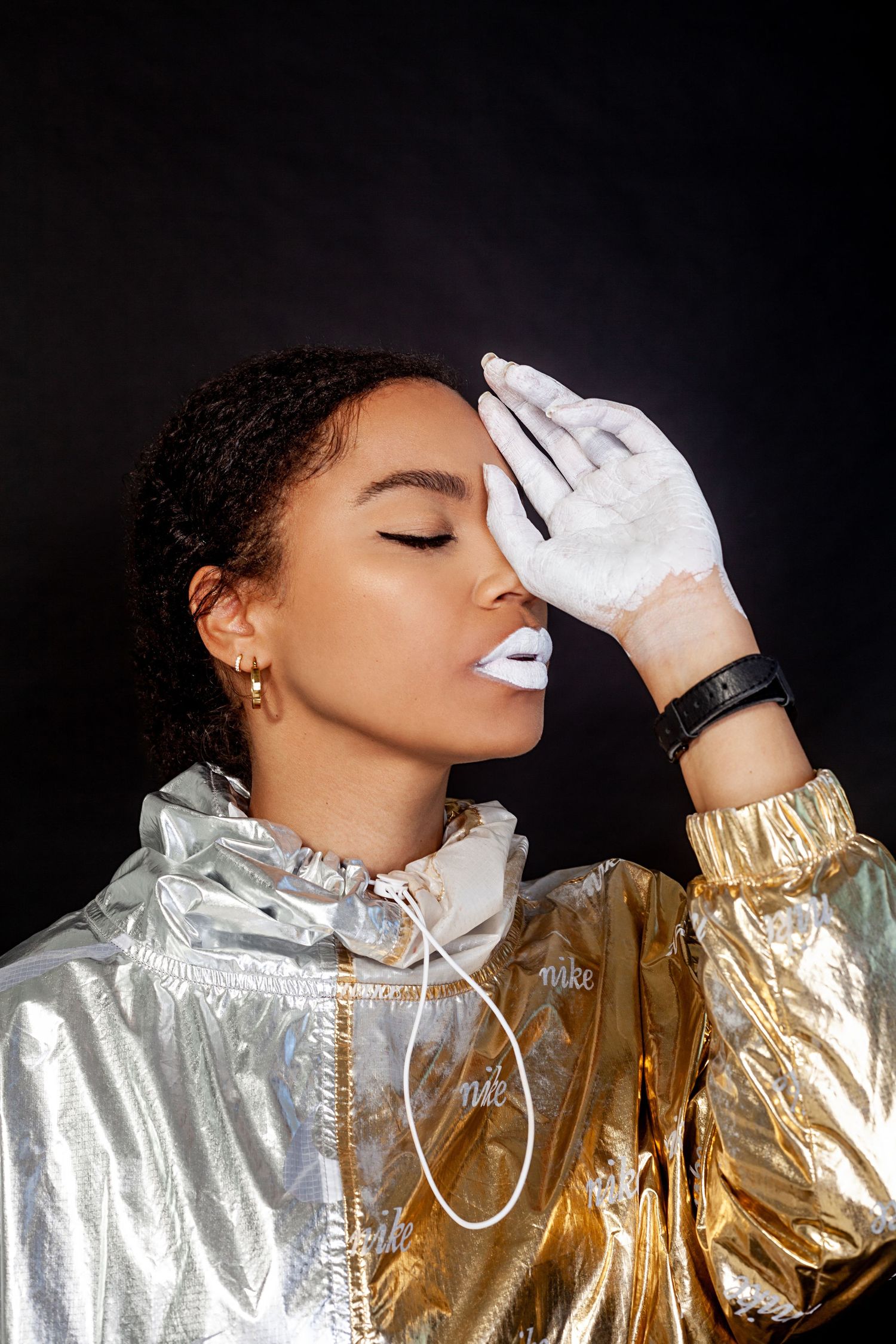 Artistic fashion photo with metallic gold jacket and white gloves creating dramatic contrast.