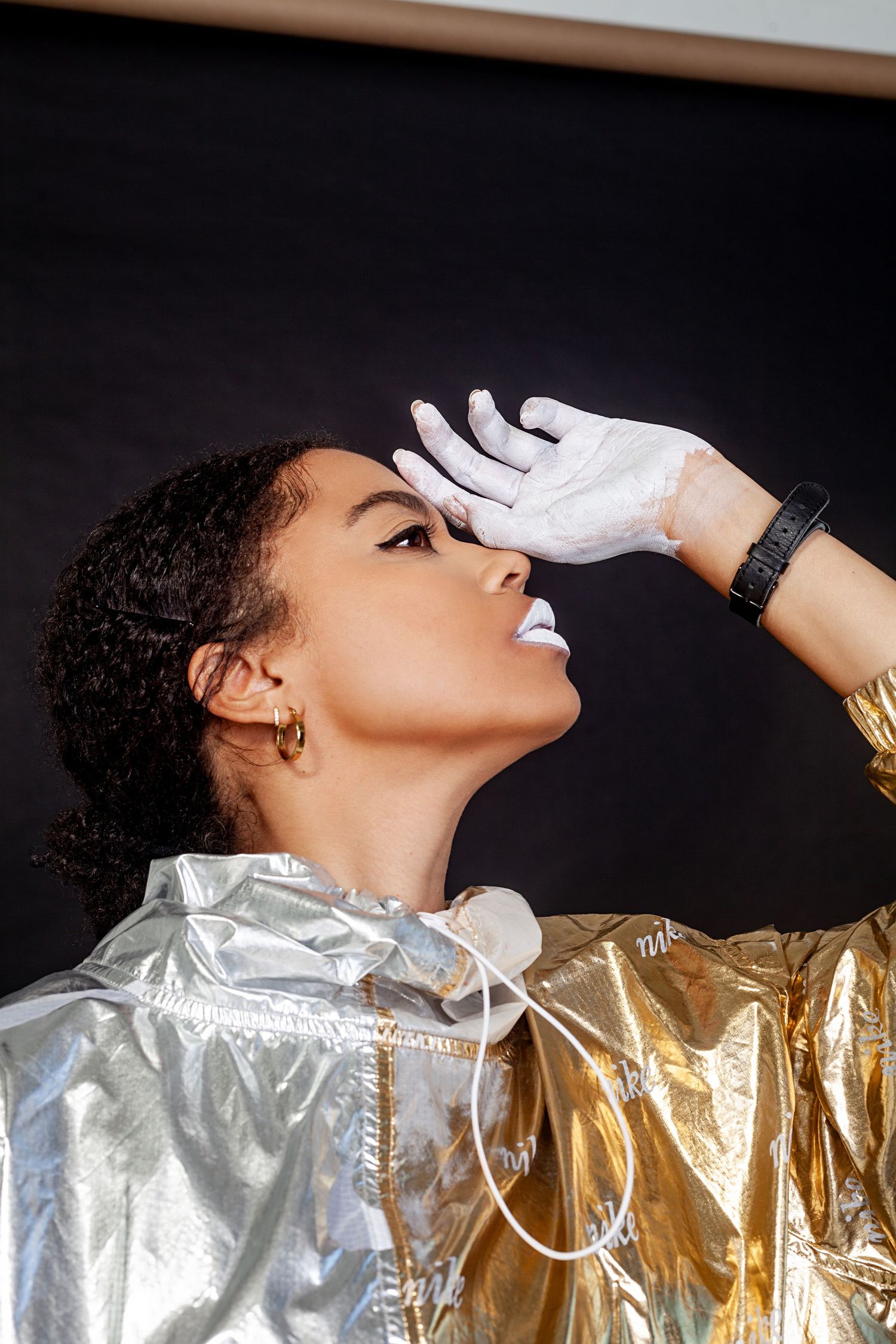 Artistic fashion shot with metallic silver and gold materials against dark background.