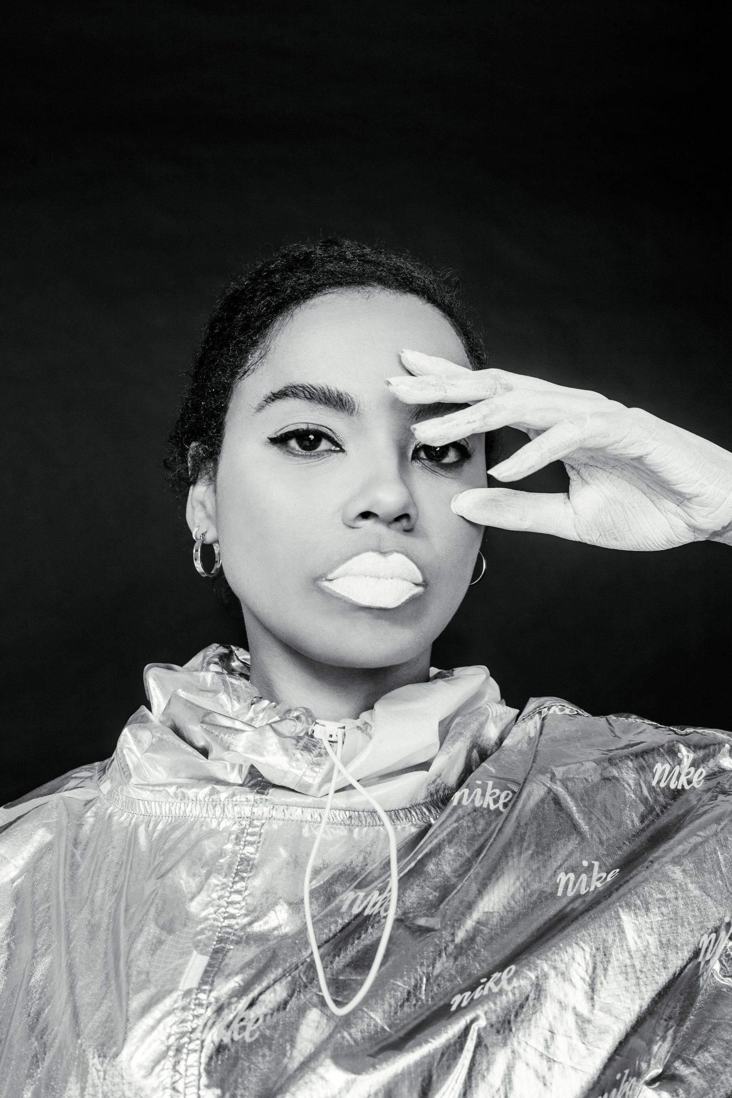 Dramatic black and white portrait with metallic jacket and white gloves creating artistic poses.