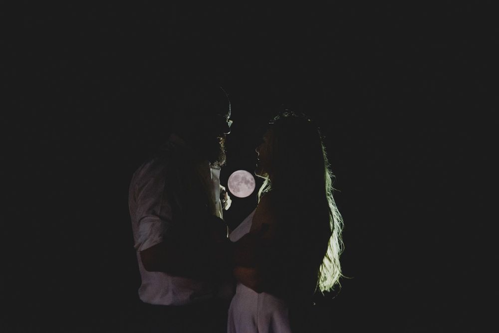 Silhouette of dancing figures illuminated by a single light against dark background.