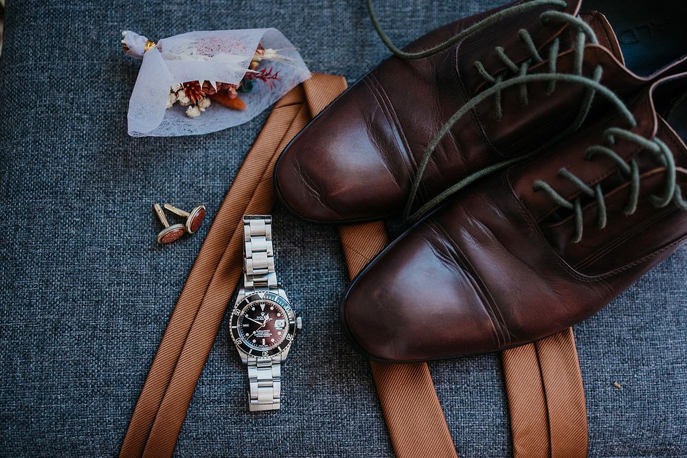 Grooms shoes tie watch and boutonniere laid out