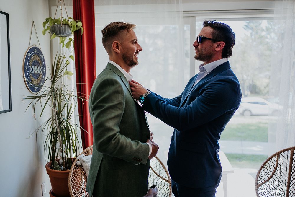 the grooms friend helping him do up his tie