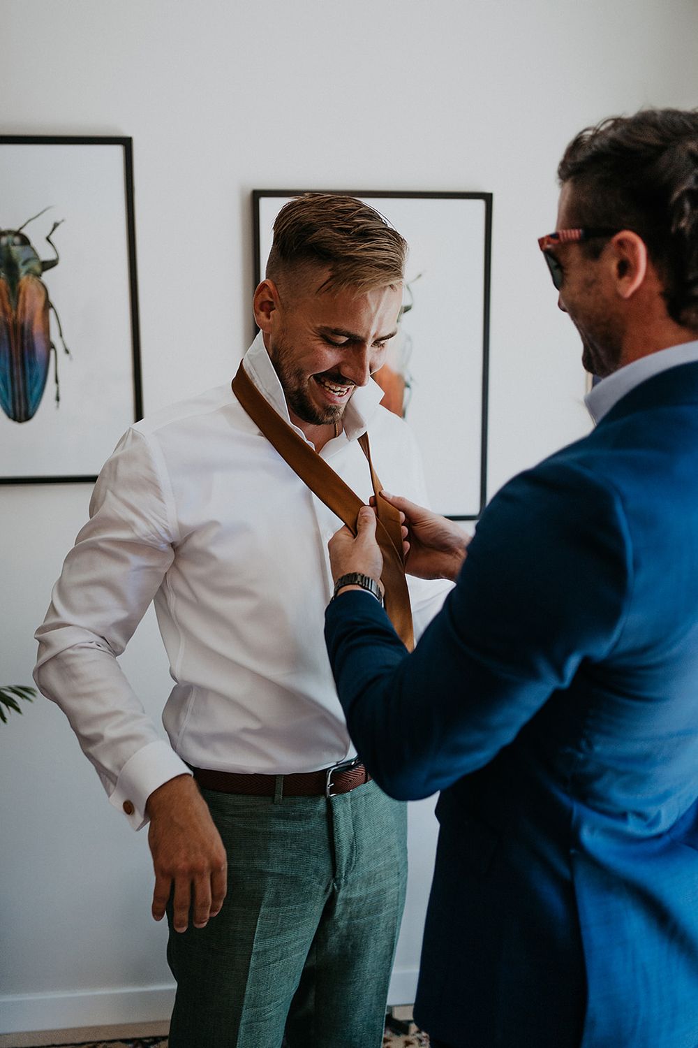 groom getting help with his tie from a friend