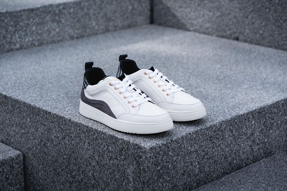 White and black athletic sneakers positioned on concrete steps.