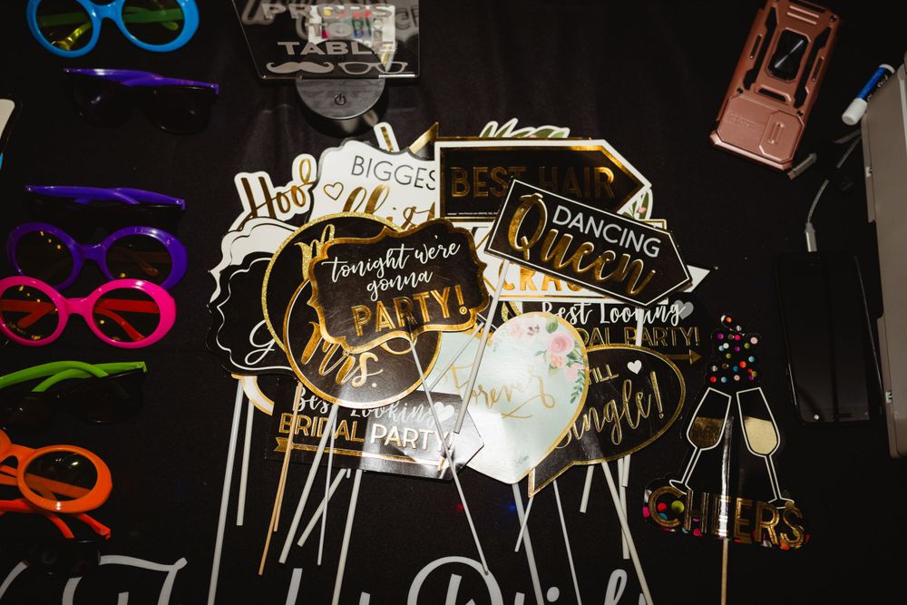 Photo booth props including colorful glasses and word signs displayed on a dark background.